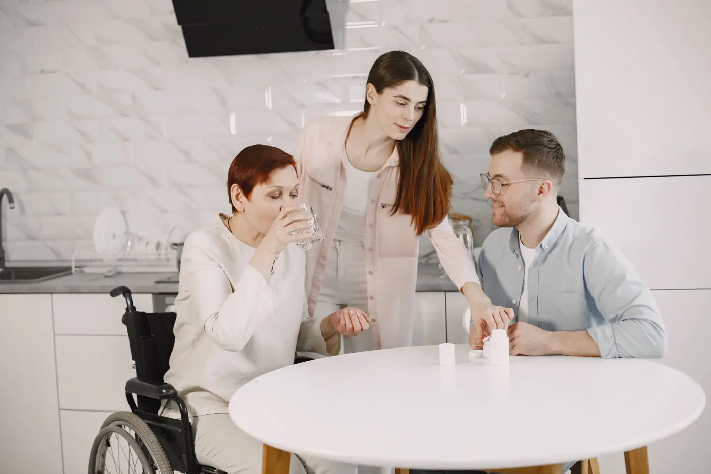 A woman in a wheelchair at the kitchen table with her family