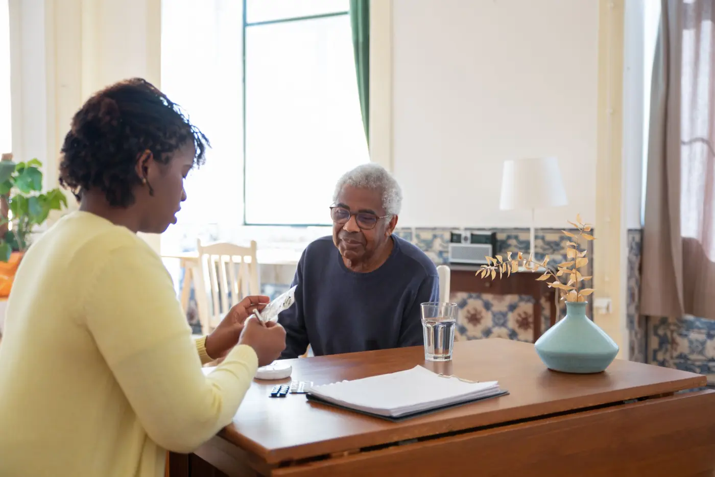 A caregiver and an older man at a dining table